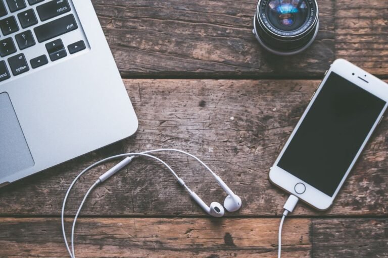 Top view of a laptop, smartphone and earphones on a wooden desk (Pexels photo by Jessica Lewis)