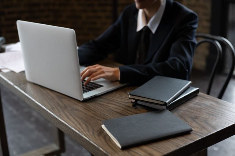 Person typing on a laptop on a hard wooden desk, a loud laptop fan fix