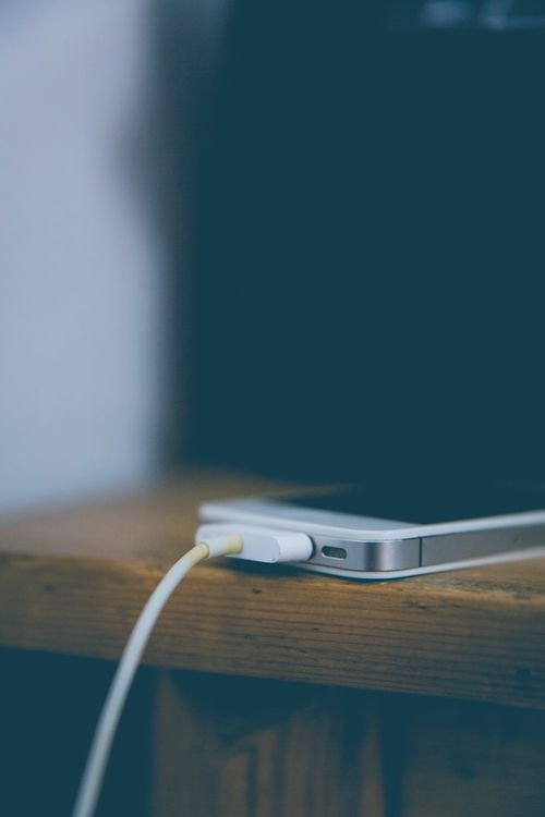 A smartphone charging on a wooden desk, left alone to charge at full speed