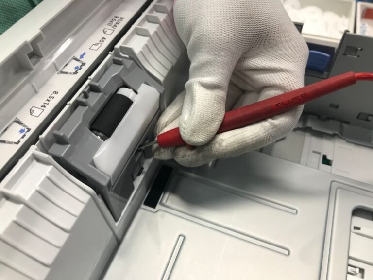 Gloved hand checking inside an open printer with a tool, a printer not printing fix.