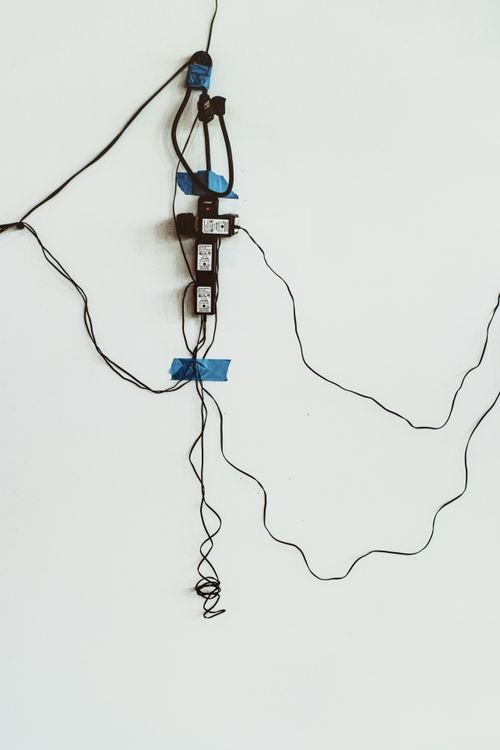 Tangled charging cables and power sockets on a wall, showing why a worn cable slows charging